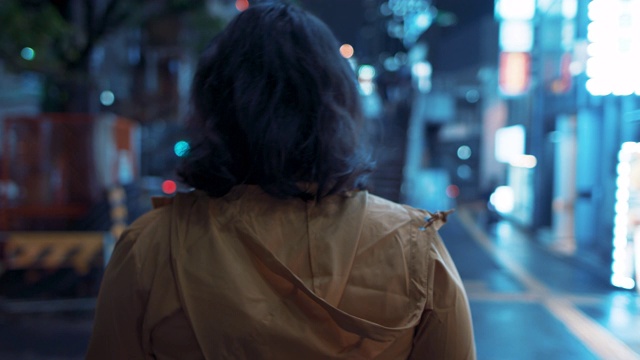 日本东京，一名穿着兜帽夹克、戴着耳机的年轻日本女子在夜晚散步视频购买
