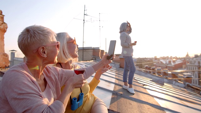 在屋顶上喝酒和拍照的女人视频素材