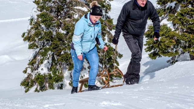 一男一女正拉着雪橇上坡视频下载