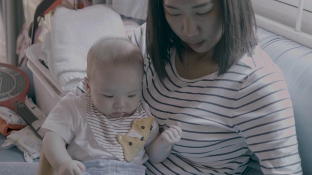 年轻的母亲把宝宝抱在客厅的沙发上用鼻子爱抚。视频素材