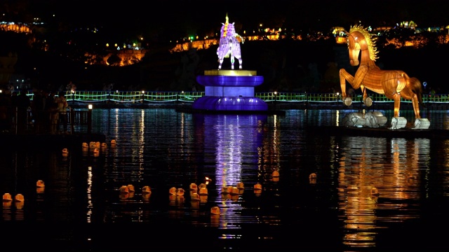 在韩国金州南江玉灯节上，不同大小的传统灯笼漂浮在南河上，背景是被灯光照亮的要塞视频下载