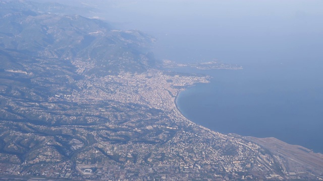 4k慢镜头从飞机窗口俯瞰法国尼斯的城市、海岸线海滩和机场。在一个晴朗温暖的夏日，从一万英尺的高空俯瞰整个城市。视频下载