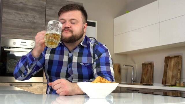 大胡子男人在厨房里喝啤酒吃薯条，卡路里，慢动作视频素材