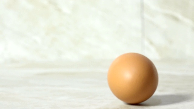 一个棕色的鸡蛋在工作台上滚动视频下载