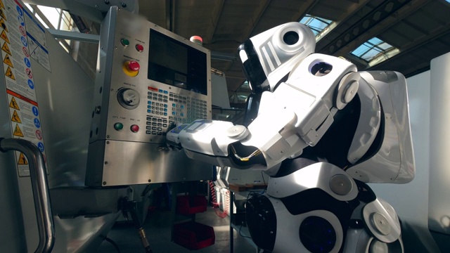 现代机器人与工厂的机器一起工作。视频下载