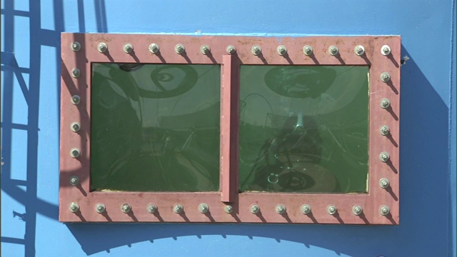 一个戴着潜水装置的焊工透过一个水箱的窗户向外张望。视频下载