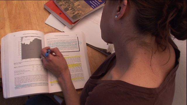 一个女人在学习的时候专注于她的大学教科书。视频下载