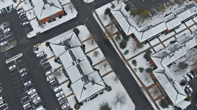 无人机的镜头低空飞过，房屋和街道被雪覆盖。视频下载