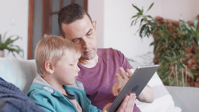 父亲和孩子在家里使用平板电脑视频下载