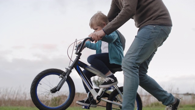 快乐的小男孩和爸爸一起学骑自行车视频下载