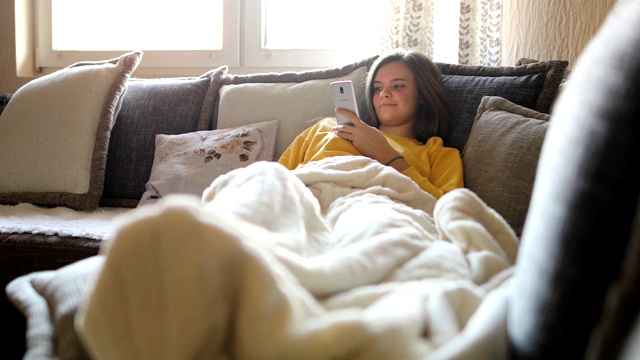幸福的女人早上在沙发上用手机视频素材