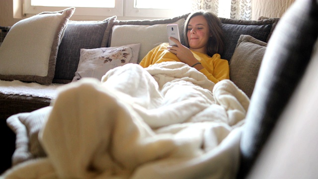 幸福的女人早上在沙发上用手机视频素材