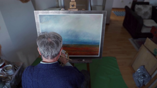 一位年长的男子正在用油彩作画视频素材