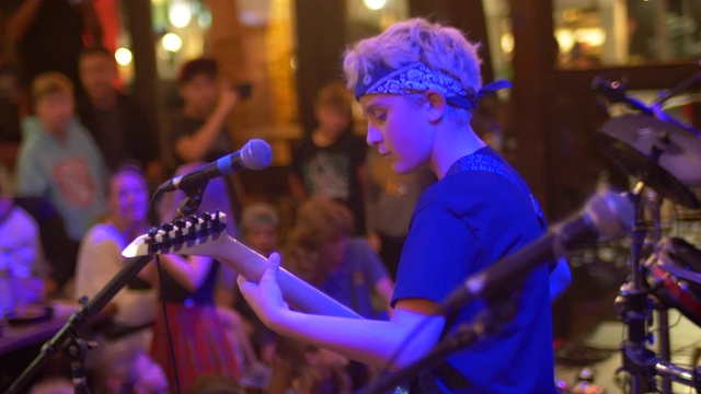 一个音乐家摇滚明星青少年在一个摇滚乐队的舞台上弹奏电子键盘钢琴和吉他。——慢动作视频下载