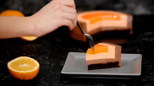 :女子吃橘子巧克力慕斯蛋糕的特写。视频下载