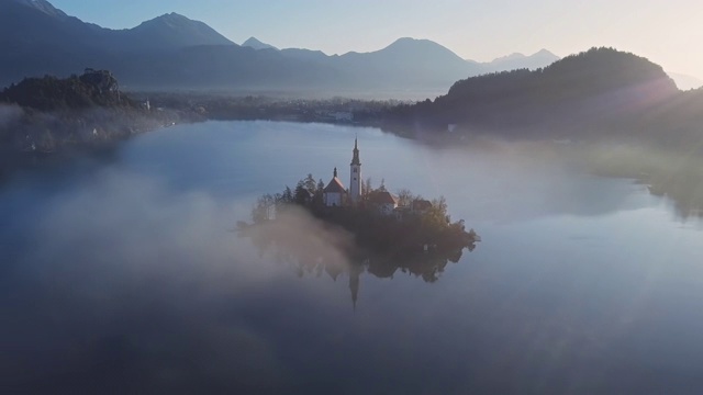 鸟瞰图的布莱德岛(布莱斯基otok)与朝圣教堂的圣母升天在湖流血在晴朗的秋天早晨与轻雾，斯洛文尼亚视频下载