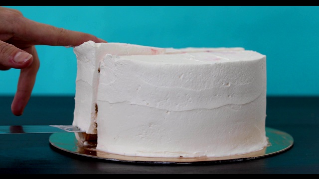 女人切了一块有奶油和海绵蛋糕层的自制蛋糕视频下载
