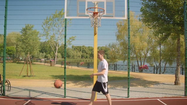 年轻漂亮的白人男性篮球运动员在球场上投一个球赢得了公园的特写视频下载