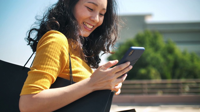 亚洲女性使用智能手机购物袋视频素材