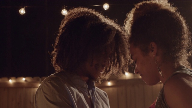 美丽的非裔美国人夫妇在串灯下诱人地跳舞视频素材
