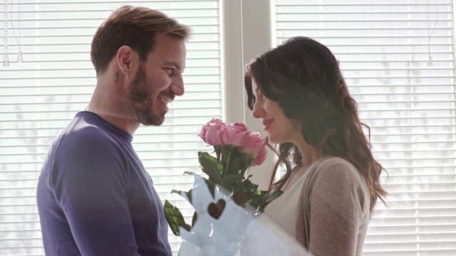 一个女人在闻丈夫送给她的一束玫瑰作为结婚纪念日视频素材
