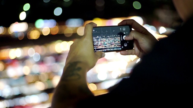 一个男人在晚上用智能手机拍照。视频素材