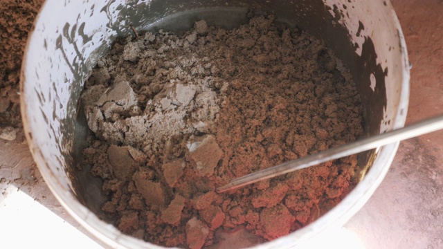 用长钻搅拌水泥胶或砂浆。工人用长钻在桶里搅拌水泥胶。砂水水泥混合视频素材