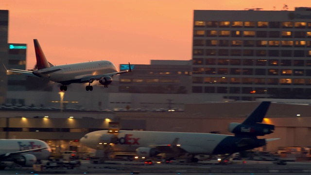 LS PAN Delta航空公司的双引擎客机在降落前最后接近洛杉矶，黄昏时经过El Segundo办公楼视频下载
