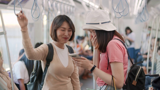 兩名女游客在火車上一邊聊天一邊使用智能手機，慢鏡頭視頻素材