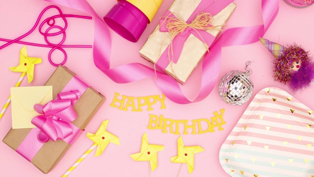 生日聚会的装饰和礼物出现在粉红色的背景-停止运动视频下载