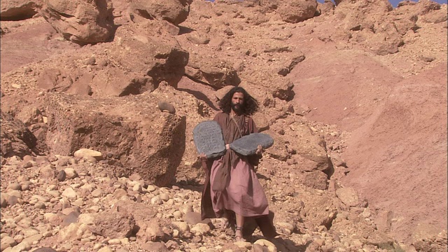 摩西扛着石碑从一座沙漠山上下来。视频素材