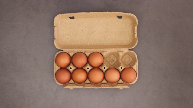 鸡蛋出现在纸板箱中，手放一个鸡蛋-停止运动视频下载