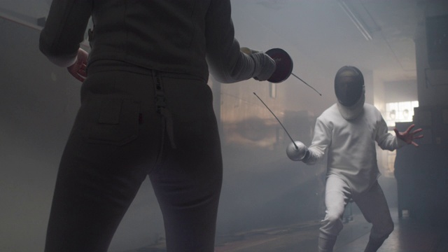 两名击剑运动员在进入攻击前在一个黑暗和阴沉的击剑体育馆跳舞视频素材