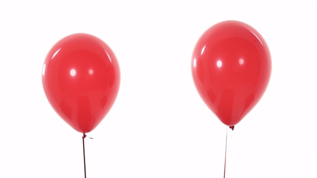 近距离拍摄的两个红色气球在空中飞行，彼此分离。孤立，在白色背景上。视频下载