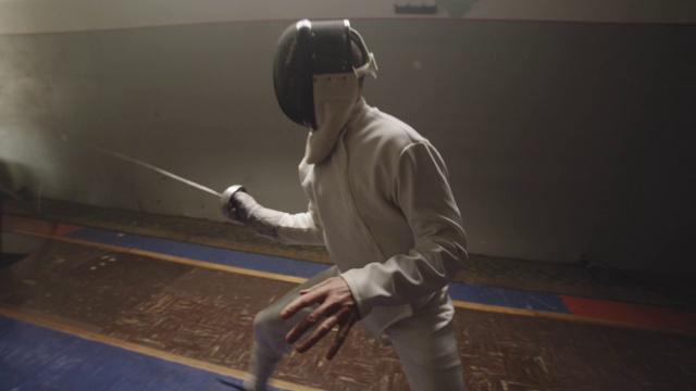 在一个黑暗和肮脏的体育馆训练的两个击剑手的镜头视频素材