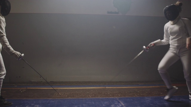 两名击剑运动员在一个黑暗而肮脏的体育馆里决斗视频素材
