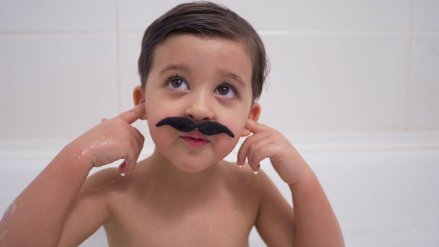 一个长着黑胡子的小男孩坐在浴室里视频素材