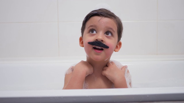 一个长着黑胡子的小男孩坐在浴室里视频素材