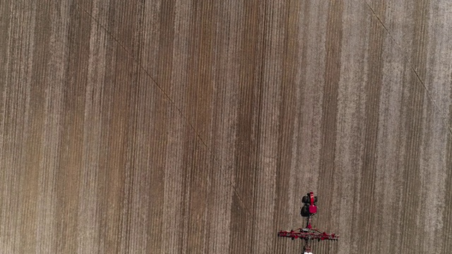 美国伊利诺斯州林登镇附近，拖拉机在春耕和施肥。无人机加速视频与向前和倾斜的相机运动。视频下载