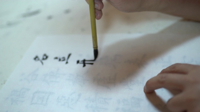 一个年轻人的手在宣纸上写中国书法视频素材