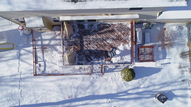 一名成年男子在一场冬季降雪后清理乡间小屋后院的露台。视频下载