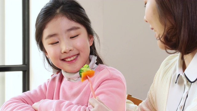 小学女孩微笑和老师与蔬菜在她的手视频素材