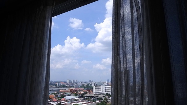 蓝天白云的城市景观，从挂着窗帘的玻璃窗往外看视频素材