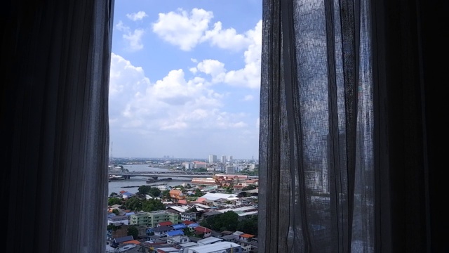 蓝天白云的城市景观，从挂着窗帘的玻璃窗往外看视频素材