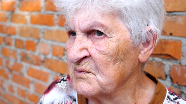 奶奶坐在外面和别人聊天。老年妇女的肖像与严肃的面部表情讲述故事。奶奶在和别人交流。慢镜头视频素材