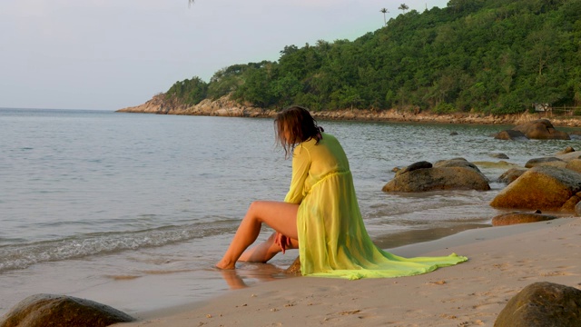 美丽的女人坐在海边的石头上视频素材
