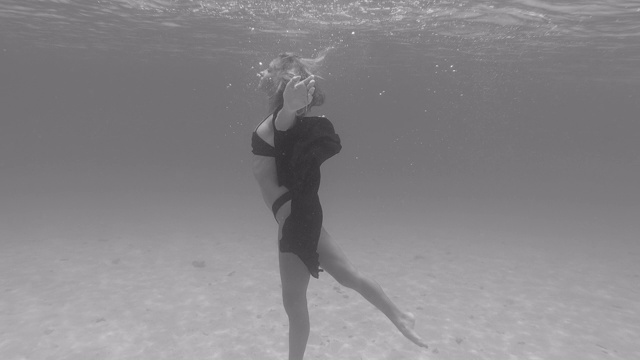 一个穿着比基尼在珊瑚礁上水下游泳跳舞的女人。——慢动作视频下载