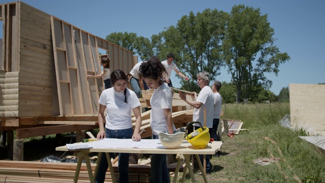 一群志愿者在一个阳光明媚的日子里在一个慈善建筑工地辛勤工作视频素材