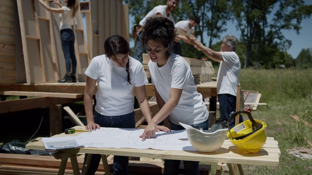 美丽的女志愿者团队看着一个住房项目的蓝图，同时非常愉快地交谈视频素材