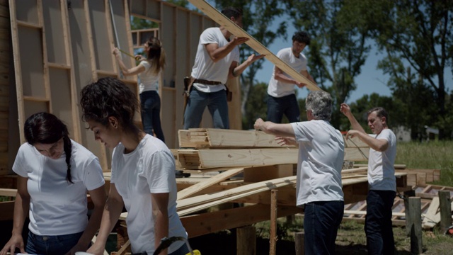 当团队在后台工作时，女性志愿者在检查住房项目的蓝图视频下载